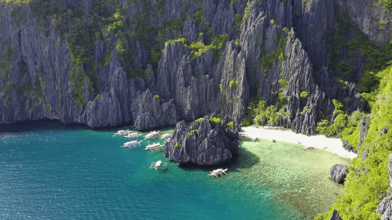 White boats on secluded lagoon white sand beach rock formations Philippines