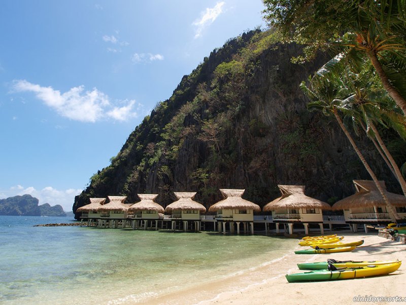 Water villas and yellow kayaks on sandy beach