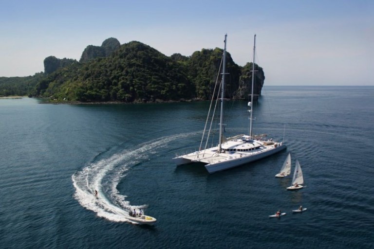 Motor boat, kayakers and sailboats around a catamaran near green island