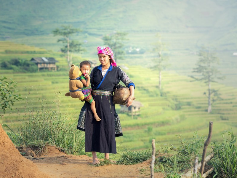 Village woman with small child with rice paddies in background